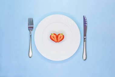 Beyaz tabakta çilek yarıları kalp. Düşük kalorili diyet kavramı. Vegeterian çiğ gıda. Sevgililer Günü konsepti.