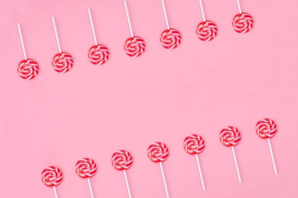 Veel kleurrijke Lollipop Candys gerangschikt in twee groepen en lege ruimte in het midden op roze achtergrond. — Stockfoto