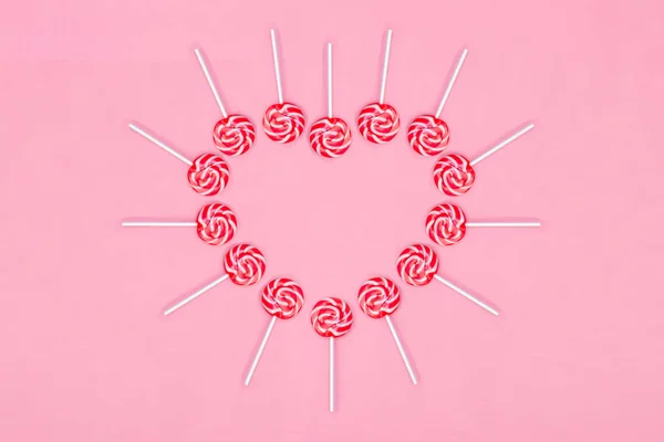 Hart gemaakt van Lollypop snoepjes op roze achtergrond, kopieer ruimte. Aftelkalender voor Valentijnsdag wenskaart — Stockfoto