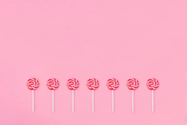 Veel kleurrijke Lollipop Candys met rode en witte strepen op roze achtergrond. Kopieer ruimte. Vlakke lay concept. — Stockfoto