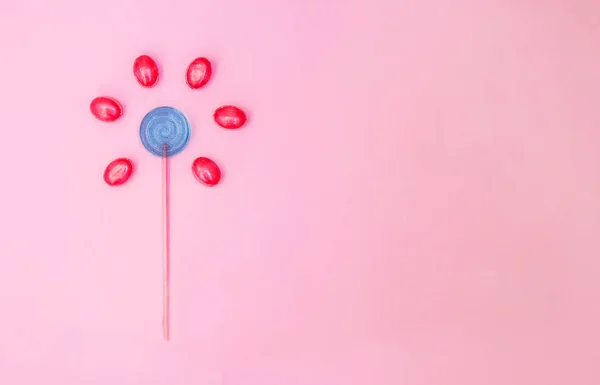 Kwiat wykonany z Lizak i cukierki na różowym tle z kopią przestrzeni. Minimalna koncepcja. — Zdjęcie stockowe