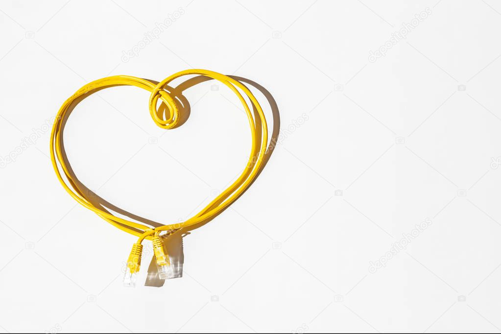 Yellow network cable folded in the shape of a heart isolated on white. Safer Internet Day. World Telecommunication and Information Society Day.