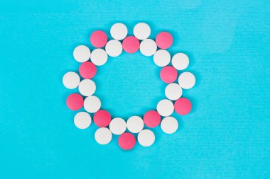 Açık mavi arka plan üzerinde beyaz ve kırmızı hapları yuvarlak çerçeve