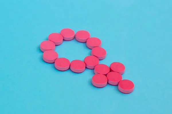 Contraceptive pills as gender symbol on blue background. Female hormone therapy