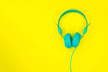 Turkuaz veya mavi kulaklıklar veya sarı arka planda kopya alanı olan bir bilgisayar kulaklığı.
