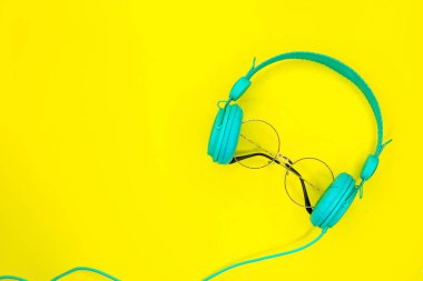 Kopya alanı ile yaz sarı arka planda yuvarlak güneş gözlüğü ve mavi kulaklıklar.