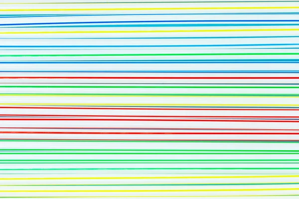 Un sacco di cannucce di plastica colorate o tubi con strisce blu, rosse, gialle e verdi. Sfondo astratto . — Foto Stock