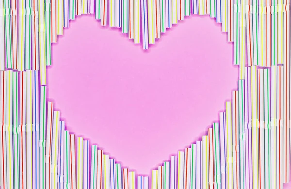 Heart frame of colored plastic straws or cocktail tubules on light blue background with copy spase.