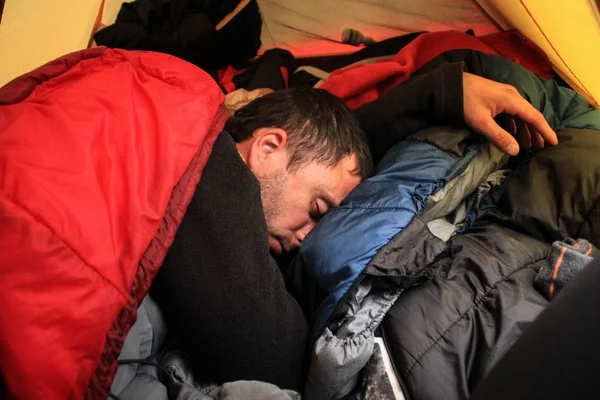 Young tourist guy sleeps deep in a sleeping bag inside a tent.
