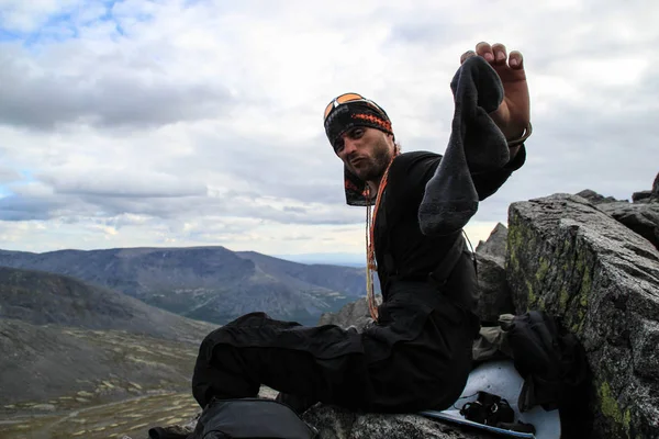 Turist genç adam dağlarda uzun bir yürüyüş sırasında eski kokmuş çorap değiştirir