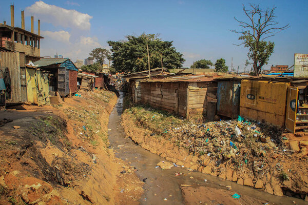 Кампала, Уганда - 22 января 2015 г.: Очень грязная река с мусором и горами пластика на берегах среди бедных домов в трущобах
.