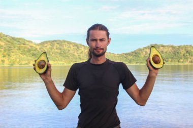 Kafkas erkek gezgin Avokado tohum ile iki yarısı Tanganika Gölü'nün arka planı tutan spor giyim beyaz.