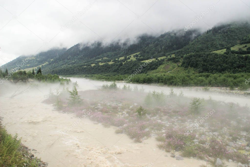 Fog spreads over the river and mountains in the early morning in Svaneti, Georgia.
