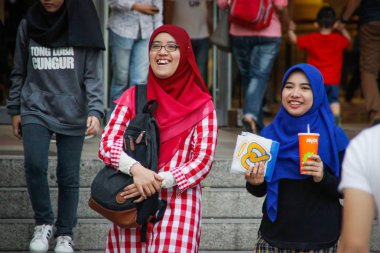 Kuala Lumpur, Malezya - 2 Nisan 2017: Parlak hijabs iki genç kız yürüyüş ve Petronas kuleleri gülüyor