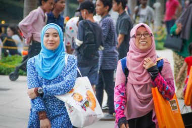Kuala Lumpur, Malezya - 2 Nisan 2017: Parlak hijabs iki genç kız yürüyüş ve Petronas kuleleri gülüyor