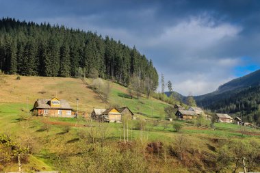 Karpatlar fırtınalı gökyüzü altında dağlar arasında köyde rahat ahşap geleneksel Ukrayna evler