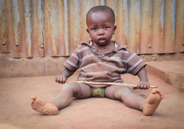 Kibera, Nairobi, Kenya - 13 Şubat 2015: bir küçük kirli siyah çocuk gecekondu katta oturur ve elinde bir sopa tutar