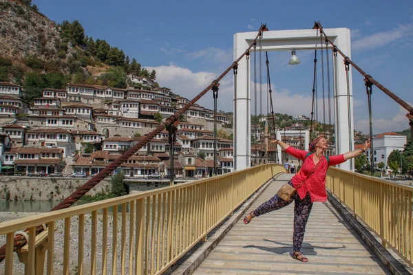 Berat, Arnavutluk - 29 Ağustos 2017: Yaya köprü Nehri üzerinde Lumi ben Ortaçağ beyaz evler ve akşam turist kız pembe bluz içinde bakan Osumit