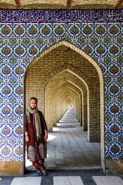 White girl tourist with a head covered stands near the beautiful gate decorated in Persian style in Tehran