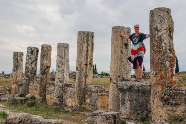 Antik antik Hierapolis sütunlar, kapıları ve mezar Pamukalle, Türkiye'de kalıntıları. Harabeleri arka plan üzerinde beyaz kız turist hippi elbise standları