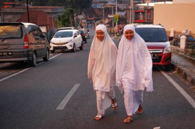 Medan, Endonezya - 20 Ocak 2018: İki Endonezyalı kız beyaz giysiler ve başörtüsü ile bir şehir caddesiüzerinde yürüyor