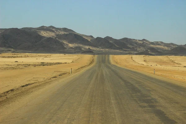 Namibya'nın güneyinde dağlar ve yol ile çöl manzaralar. Kurak mevsim, kuru bitki örtüsü doğal bir arka plan.
