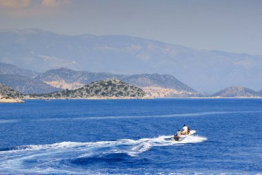 Bodrum, Türkiye - 16 Haziran 2017: Akdeniz'de kaya ve dağların arka planına karşı motorlu tekne.
