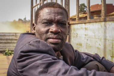 Kampala, Uganda - 3 Şubat 2015: Orta yaşlı siyah bir adamın portresi. Kirli ceketli işçi kamyonu.