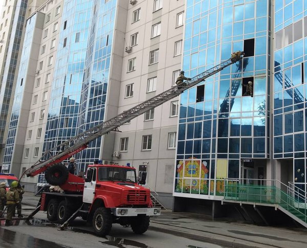 lifeguards climb the fire escape of a car through the window of a high-rise building