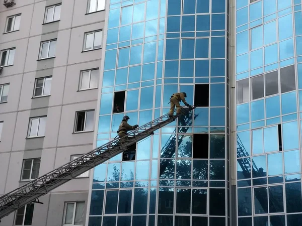 lifeguards climb the fire escape of a car through the window of a high-rise building