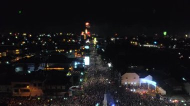 İnsanlar kalabalık ve havai fişek gösterisi ile Yogyakarta Anıt veya Tugu Jogja manzaralı geriye doğru uçan hava görüntüleri dron