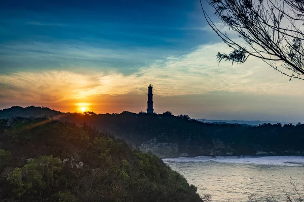 Baron Sahili, Java Adası, Endonezya 'da deniz feneri siluetiyle güzel bir gün doğumu gökyüzü.