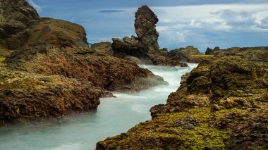 Siung sahilindeki kaya kulesi hareket bulanık dalga kanalı ve mavi gökyüzü arka planıyla