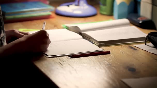 学校的男孩少年学习做作业 男孩坐在桌旁 晚上在笔记上写字 — 图库视频影像