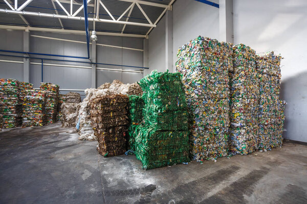 Plastic pressed polyethylene bales and jar bottles at finished product warehouse on waste hazardous processing plant. Separate garbage collection. Recycling and storage of waste for further disposal. 