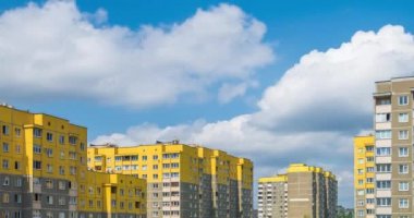 Zaman atlamalı küçük sarı çok katlı apartmanlar arka planı beyaz kabarık haddeleme bulutlar