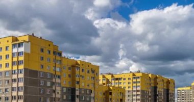 Zaman atlamalı küçük sarı çok katlı apartmanlar arka planı beyaz kabarık haddeleme bulutlar