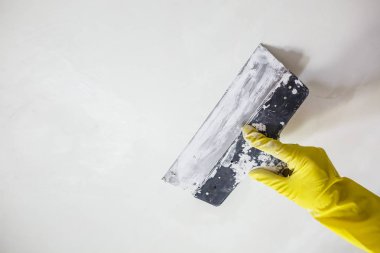 sarı eldiven spatula ile sıva veya macun beyaz duvarındaki bir delikle yama macun bıçağı tutan işçinin elinde. İç oda daire binasında tadilat tadilat ve onarım işlemi