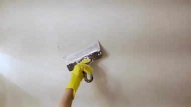 sarı eldiven spatula ile sıva veya macun beyaz duvarındaki bir delikle yama macun bıçağı tutan işçinin elinde. İç oda daire binasında tadilat tadilat ve onarım işlemi