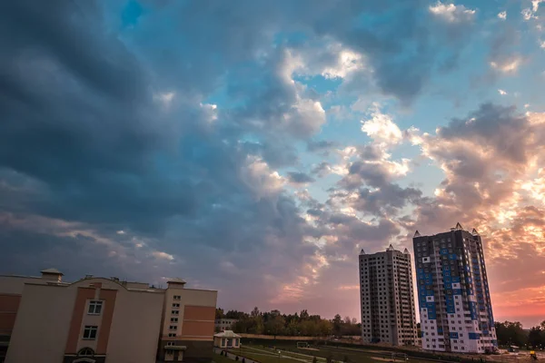 夜の多階建てのアパートの建物の背景に素晴らしい夕日のふわふわの巻き毛圧延雲 — ストック写真