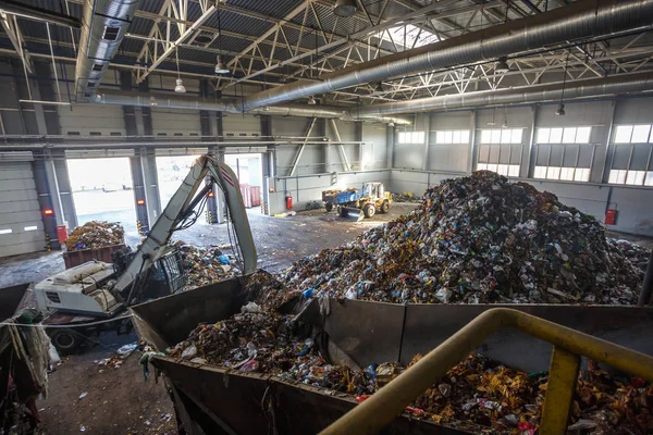 Excavator on primary sorting of garbage at waste processing plant. Separate garbage collection. Recycling and storage of waste for further disposal. Business for sorting and processing of waste.