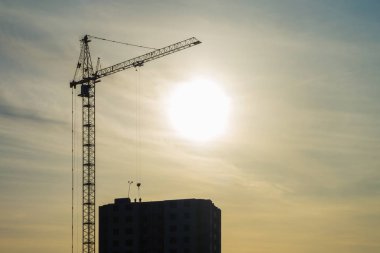 kule vinç ve tamamlanmamış çok katlı yüksek binalar inşaat alanı içinde güzel gün batımı batan güneşin ışınları altında silüeti