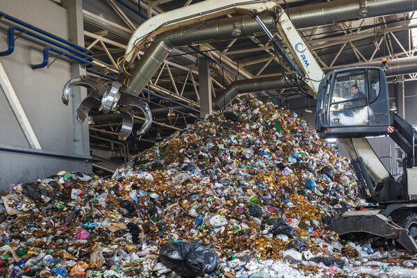 GRODNO, BELARUS - MAY 2018: Excavator on primary sorting of garbage at waste processing plant. Separate garbage collection. Recycling and storage of waste for further disposal. 