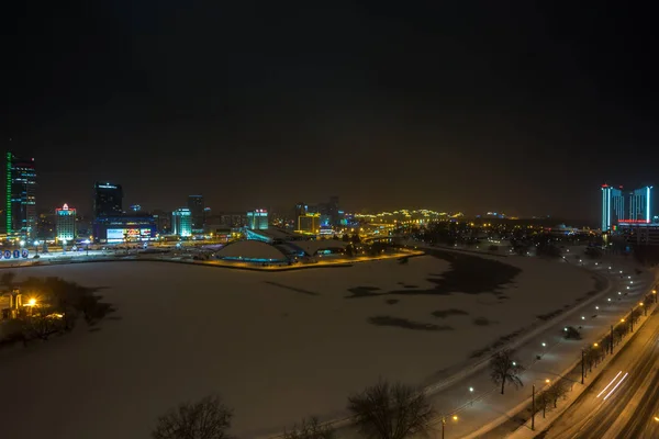 Μινσκ, Λευκορωσία - Δεκεμβρίου 2018: φώτα της πόλης τη νύχτα. Ουρανοξύστης φως αντανακλάται στο νερό λίμνης — Φωτογραφία Αρχείου