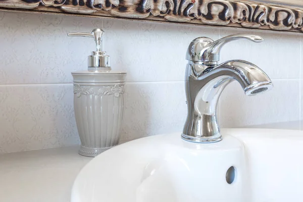 Sabonetes e dispensadores de shampoo na pia da torneira de água com torneira no banheiro caro loft — Fotografia de Stock