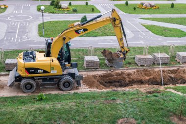 GRODNO, BELARUS -  SEPTEMBER 2018: Excavator digs a pit and loads the sand on a dump truck clipart