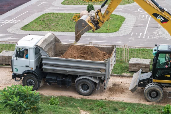 Grodno, Vitryssland - September 2018: Grävmaskin gräver en grop och laster sanden på en dump truck — Stockfoto