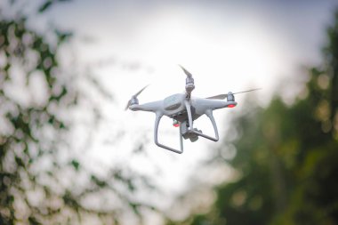 Kamera yeşil orman arka plan üzerinde beyaz uçan quadrocopter