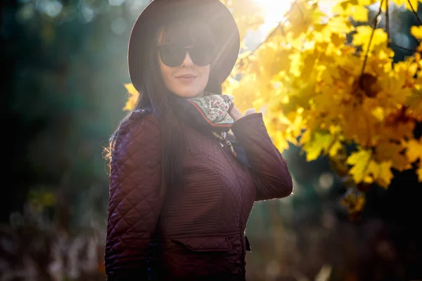 Al aire libre de cerca retrato modelo de gran tamaño hermosa chica morena con sombrero y gafas de sol mirando a la cámara en el bosque de otoño como fondo — Foto de Stock