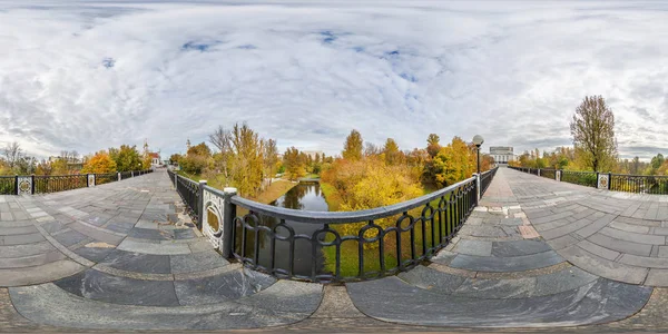 มุมมอง 360 องศาบนสะพานคนเดินข้ามแม่น้ําเล็ก ๆ ในสวนสาธารณะเมืองฤดูใบไม้ร่วงในภาพสี่เหลี่ยมผืนผ้าเท่ากัน พร้อมสําหรับเนื้อหาความเป็นจริงเสมือน AR VR — ภาพถ่ายสต็อก